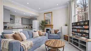 A living room with a sofa, coffee table, and a television. - Kensington Retreat, 1 min From Station (London)