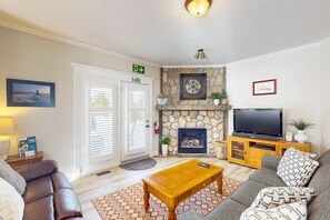 Una sala de estar con chimenea, televisión, sofá, mesa de centro y una puerta con letrero de salida.