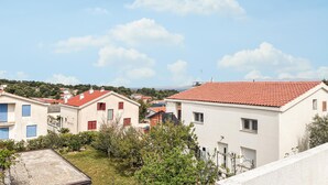 Ett bostadsområde med hus som har röda tegeltak, en klar himmel och ett kuperat landskap i bakgrunden.