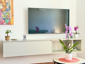 Ein modernes Wohnzimmer mit Flachbildfernseher, einer Anmeldeinformation und Topfpflanzen.