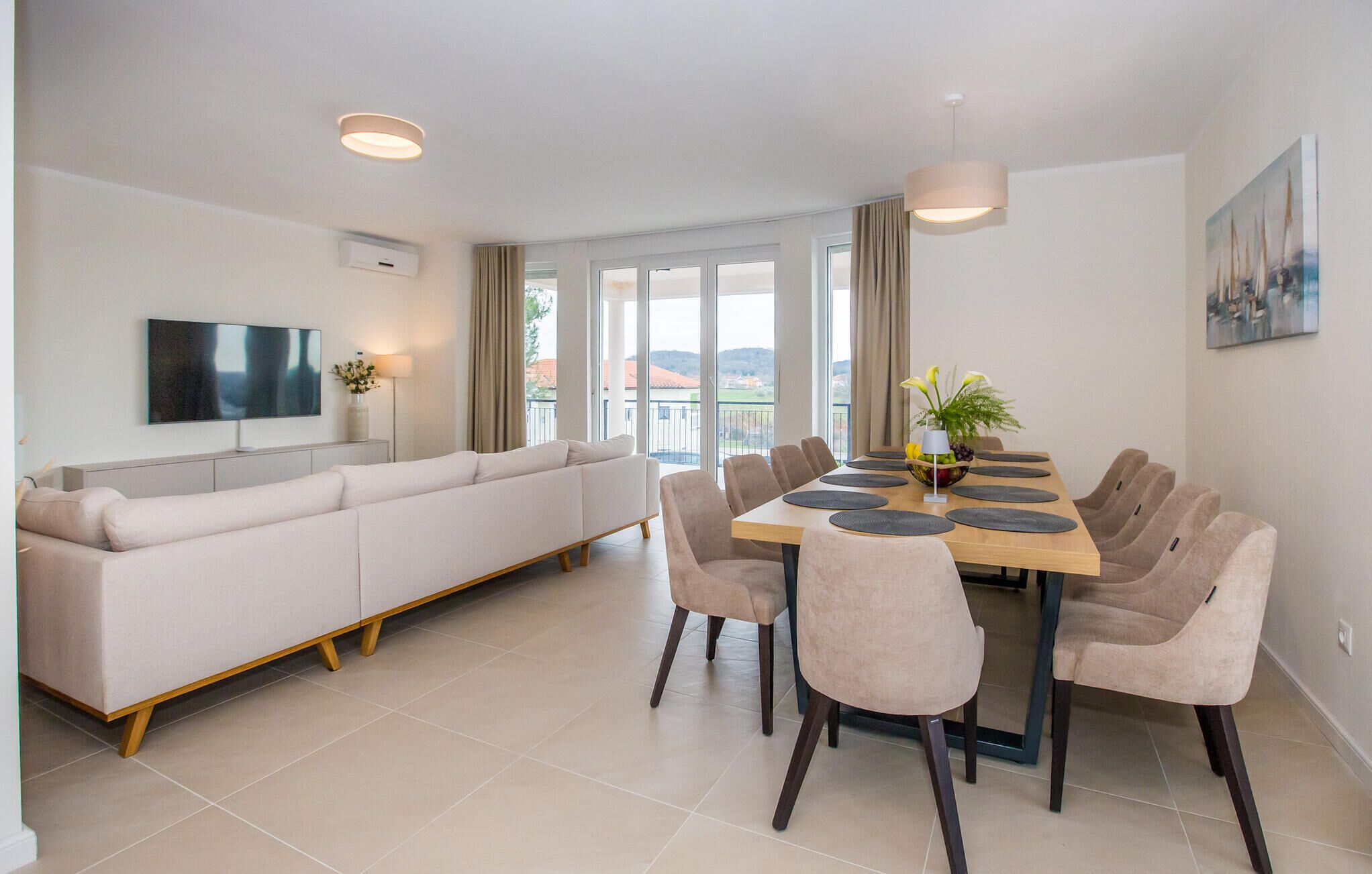 A modern living room with a sofa, dining table, chairs, and a TV.