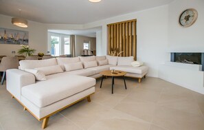 A modern living room with a sectional sofa, a round coffee table, and a decorative wall clock. - Lovely home in Porec with sauna (Porec)