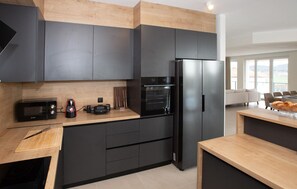 A modern kitchen with dark cabinetry, a built-in oven, a microwave, and a coffee maker. - Lovely home in Porec with sauna (Porec)