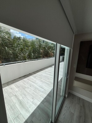 A balcony with a view of palm trees, a sliding glass door, and a tiled floor. - Luxury Family 3BR Apt in Bay Harbor Islands near Beach, Shops and Dining Area (Bay Harbor Islands)