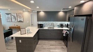 Een moderne keuken met grijze kastjes, een centraal eiland en een roestvrijstalen koelkast.