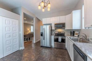 A modern kitchen with white cabinets, stainless steel appliances, and a granite countertop. - Charming Historic Ely Retreat - Walk to Downtown & Gateway to BWCA (Ely)