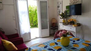 A room with a bed, a TV, a desk, a chair, and a door leading to a balcony. - Hand in hand (Le Houga)