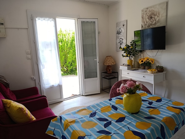 Una habitación con cama, televisión, escritorio, silla y puerta que da a un balcón.