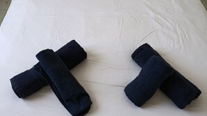 A bed with two pillows, a wooden headboard, and two rolled-up towels on the bed. - Hand in hand (Le Houga)