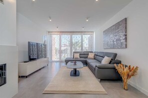 Ein modernes Wohnzimmer mit einer Couch, einem Couchtisch und einem Fernseher.