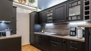 Cozinha moderna com armários escuros, bancada de madeira e cafeteira à mostra.