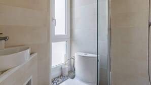 Et badeværelse med toilet, bruser og badekar.