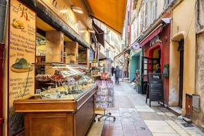 A narrow street with shops, a food display, and a sign for 'Perla'. - Peaceful haven in the heart of Old Nice (Nice)
