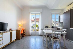 Un apartamento moderno con comedor, cocina y televisor a la izquierda.
