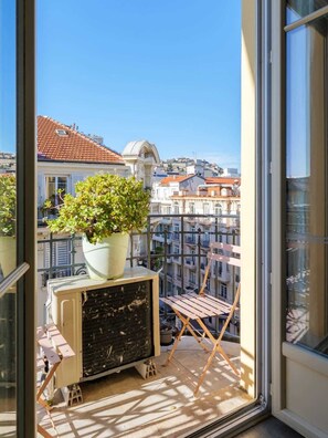 Un balcon avec un pot de fleurs, une chaise et un radiateur.