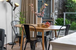A dining area with a round table, black chairs, a vase with flowers, a teapot, and a lamp. - Hamilton Lake Haven - Great Location (Hamilton)