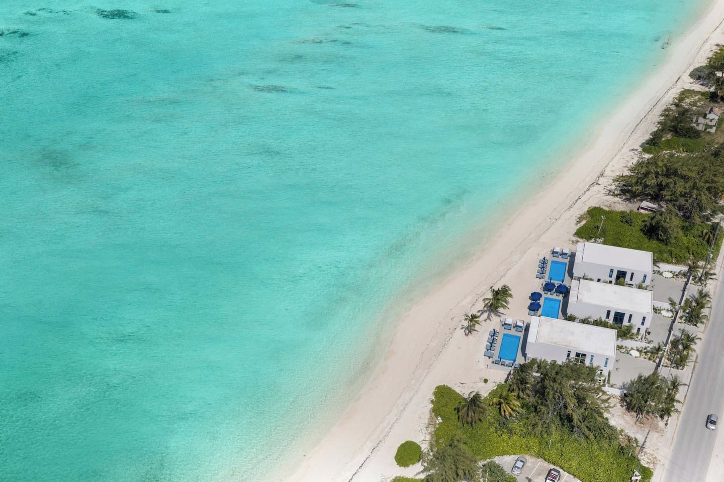 A coastal property with a beach, a pool area, and a road.