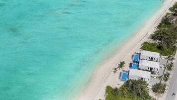 A coastal property with a beach, a pool area, and a road.
