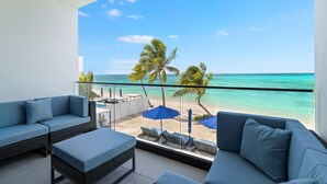 Un balcon avec vue sur la plage, un espace salon extérieur et une piscine.