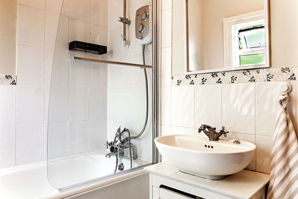 A modern bathroom with a glass-enclosed shower, a white sink, and a mirror above the sink.