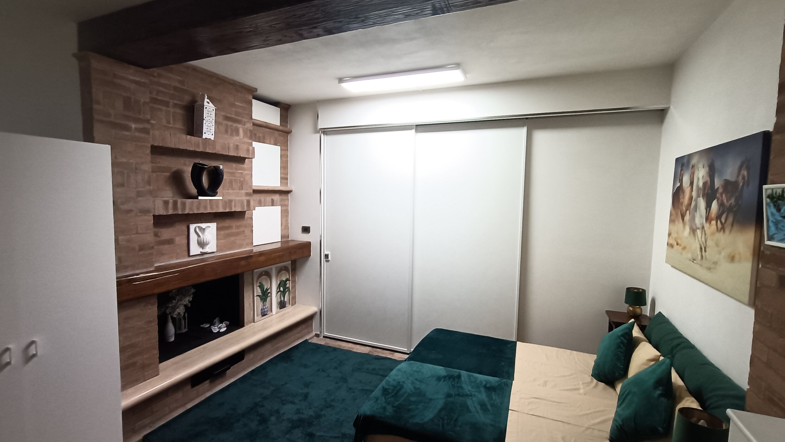 A room with a brick fireplace, a sliding closet door, and a painting on the wall.