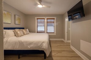 A bedroom with a bed, a ceiling fan, a window with blinds, and a wall-mounted air conditioning unit. - Spacious 3BR Duplex - Walk to Armature + Riverwalk (Tampa)