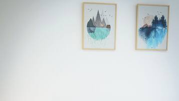 Una cama bien tendida con ropa de cama a rayas, un cabecero de madera y dos obras de arte colgadas en la pared que representan escenas naturales.