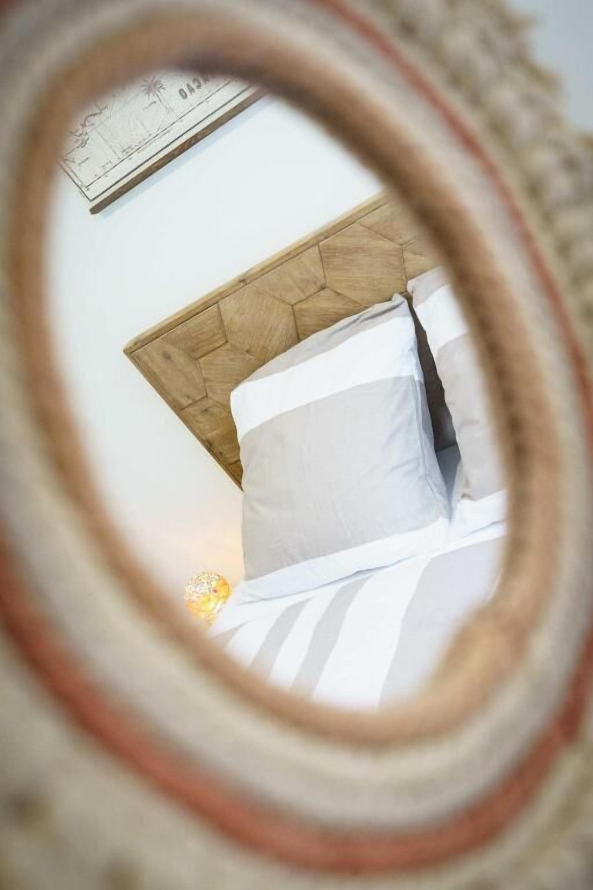 Een bed met een houten hoofdbord en wit beddengoed.