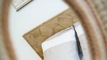 Een bed met een houten hoofdbord en wit beddengoed.