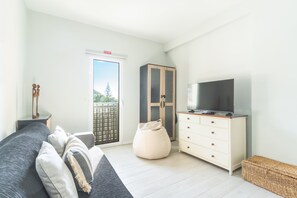 A modern bedroom with a bed, a television, a wardrobe, and a view of the outdoors. - Bays Secrets Apartment by Atlantic Holiday (Machico)