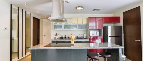 Una cocina moderna con una isla central, electrodomésticos de acero inoxidable y armarios rojos.