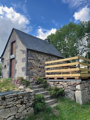 Un bâtiment en pierre avec une porte en bois et des marches menant à l’entrée.