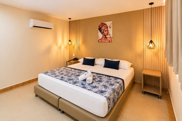 A hotel room with a bed, bedside tables, an air conditioning unit, a painting, and pendant lights. - Vadamar Hotel Collection Rodadero (Santa Marta)