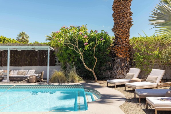 A swimming pool with lounge chairs, a covered seating area, and a palm tree. - Palm Springs Movie Colony | Designer Pool Home + Private Casita, Sleeps 10 (Palm Springs)
