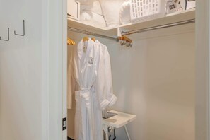 A white robe hanging on a wooden hanger, a white baby changing station, and a white laundry basket on a shelf. - Palm Springs Movie Colony | Designer Pool Home + Private Casita, Sleeps 10 (Palm Springs)