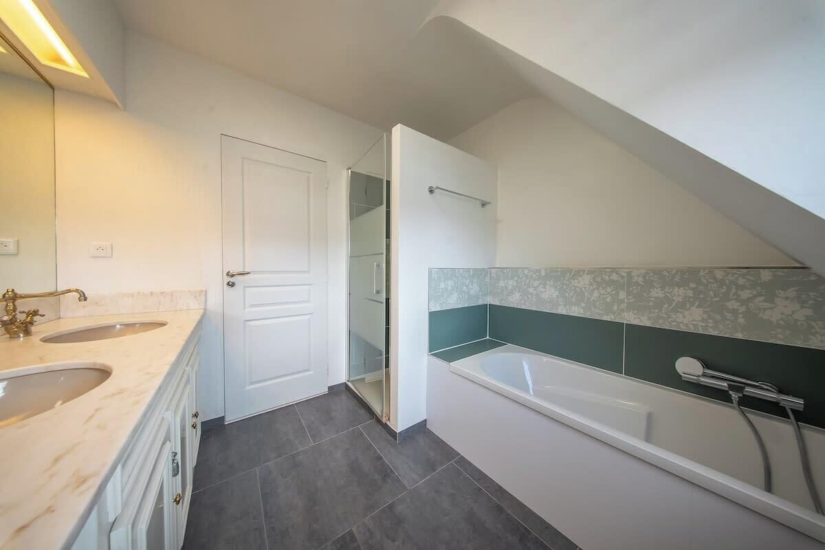 Un baño moderno con lavamanos doble, bañera y ducha.