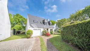 Een huis met een verharde oprit, een kleine tuin en een haag.