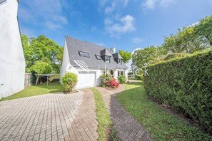 A house with a paved driveway, a small garden, and a hedge. - Villa moderne en impasse, le bonheur en famille (Larmor-Plage)