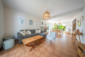 A living room with a sofa, a wooden coffee table, a dining area with a table and chairs, and a fireplace. - Villa moderne en impasse, le bonheur en famille (Larmor-Plage)
