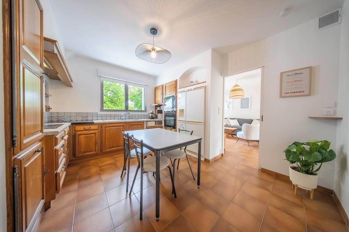Una cocina amplia con armarios de madera, una mesa de comedor y una planta en maceta.