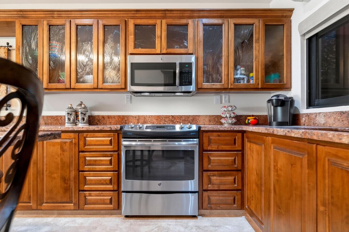 A kitchen with wooden cabinets, a stainless steel oven, a microwave, and a coffee maker.