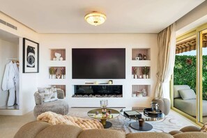 Ein modernes Wohnzimmer mit großem Flachbildfernseher, Kamin, Sofa und Couchtisch.