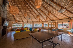 Eine großzügige Lounge mit Tischtennisplatte, bequemen Sitzgelegenheiten und einer Strohziegel-Decke.