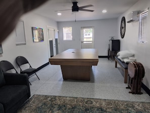 A conference room with a large table, chairs, a ceiling fan, a television, and a clock on the wall.