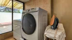 A laundry area with a washing machine and an iron on a table. - Casa Azteca (Mexico City)