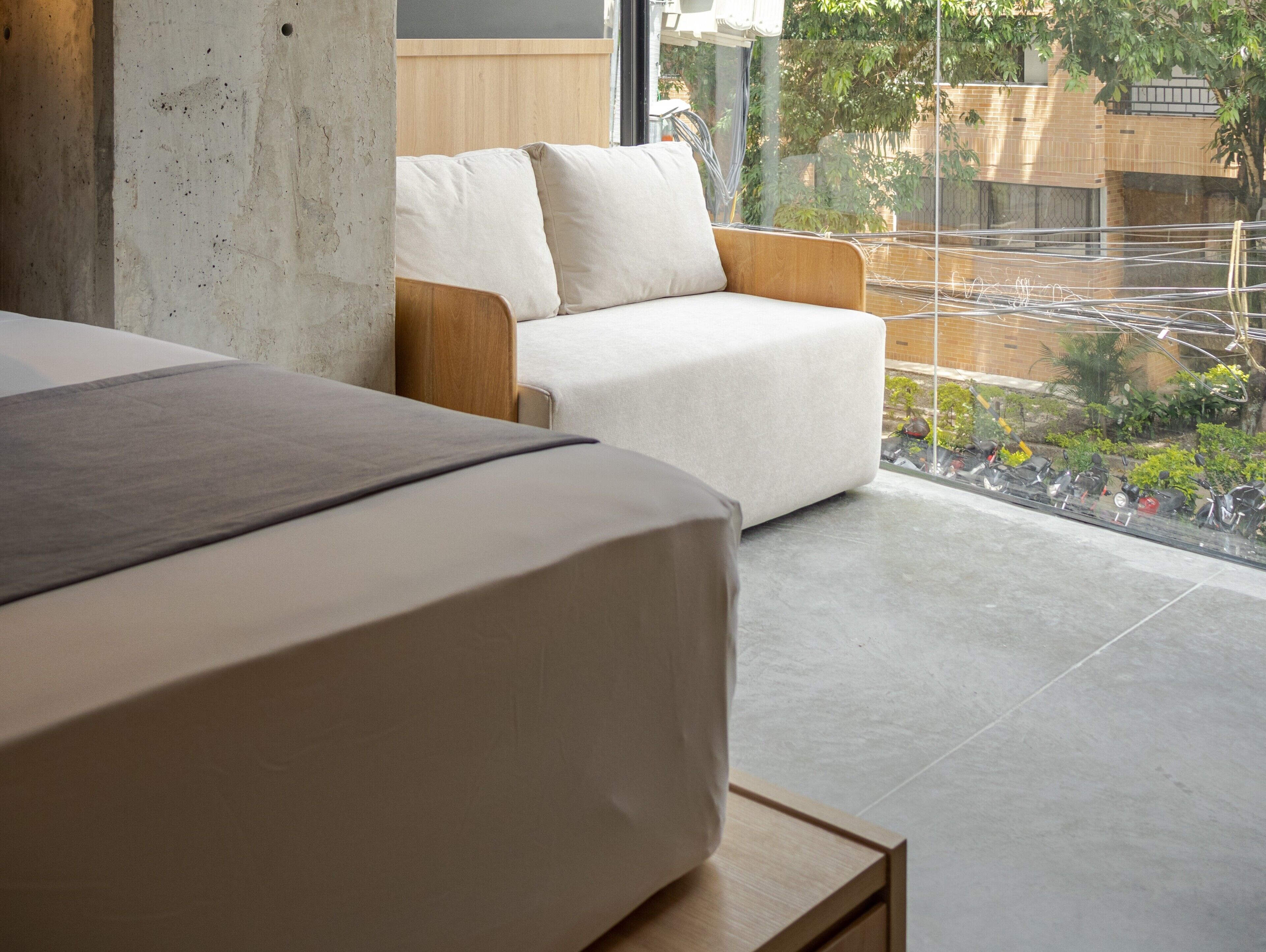 Un dormitorio moderno con cama, sofá y vistas al exterior.