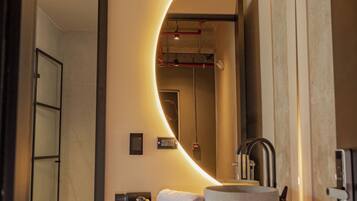 A modern bathroom with a large mirror, a sink, and a towel rack.