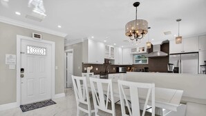 A modern kitchen with white cabinetry, a central island, and pendant lighting. - Coconut Oasis  Near Beach (Lauderdale by the sea)