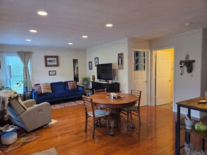 A living room with a blue sofa, a dining table, and a TV. - Cozy 2-bedroom home in SW Virginia near the New River & 20 minutes to Blacksburg (Pembroke)