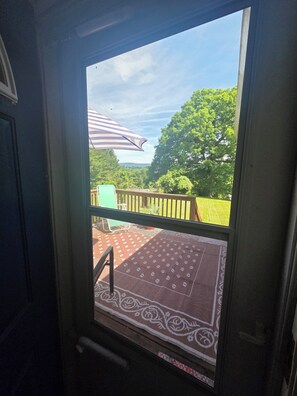 A view through a window with a view of a deck, a patterned rug, and a striped umbrella. - Cozy 2-bedroom home in SW Virginia near the New River & 20 minutes to Blacksburg (Pembroke)